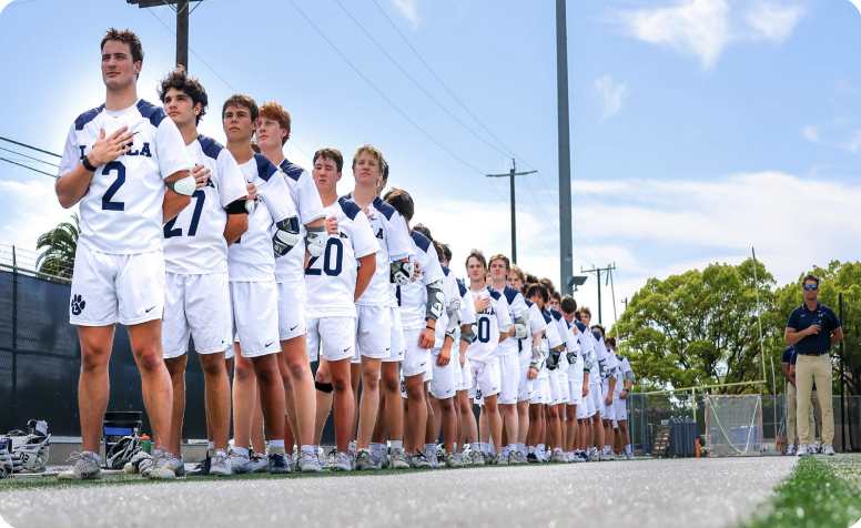 VARSITY TEAM HONORS the flag on Smith Field before facing Crespi
